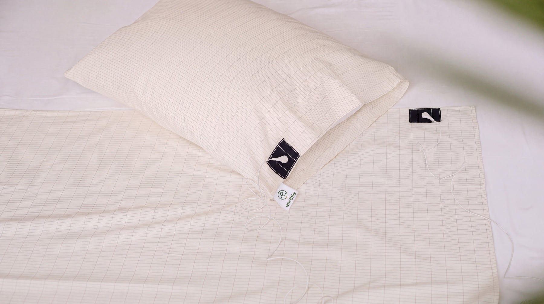 Earthing sheet and pillowcase showing the diamond pattern of the silver thread on a made bed