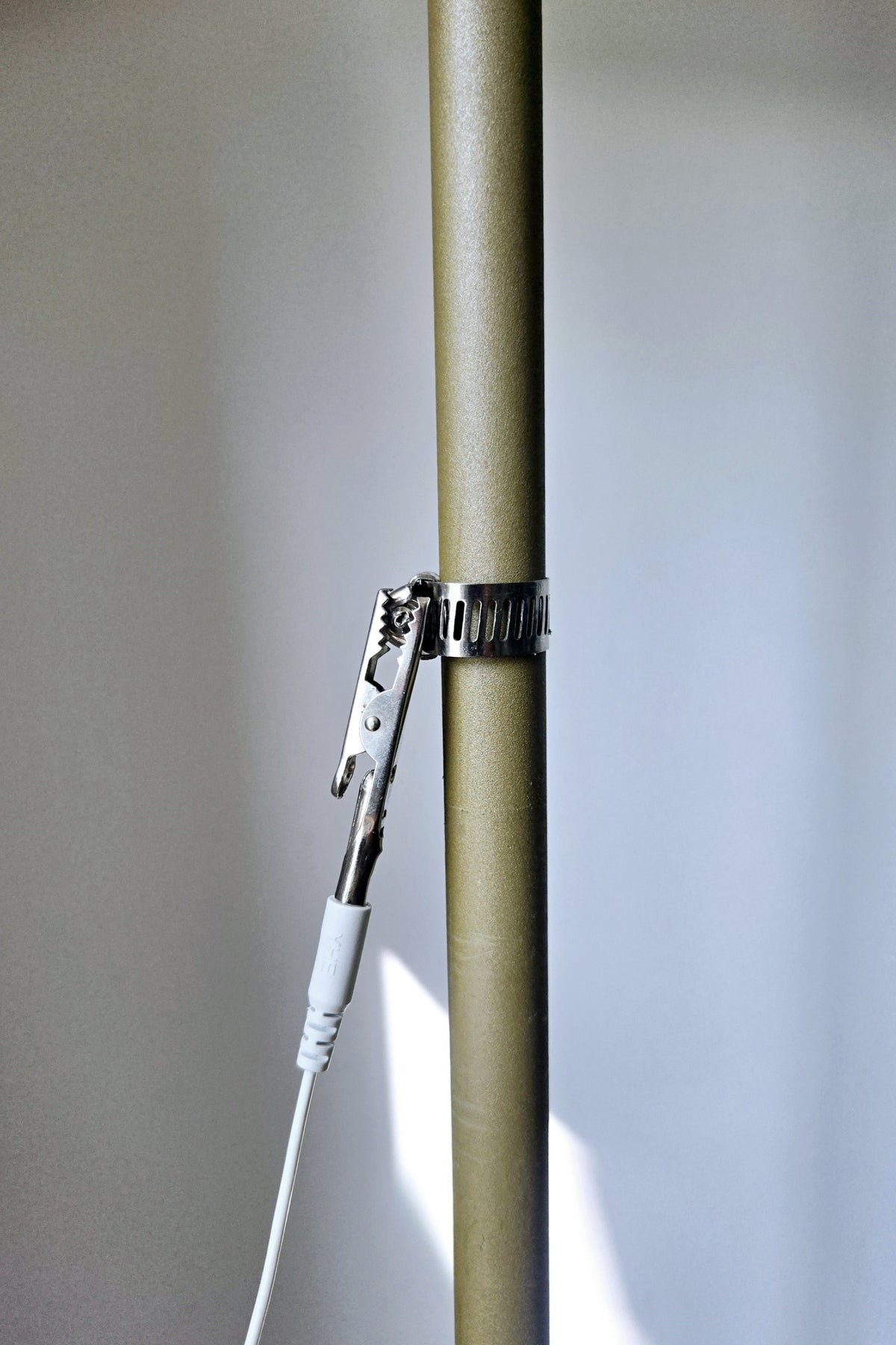 Earthle crocodile clip attached to a bare heating pipe, with the earthing cable connected