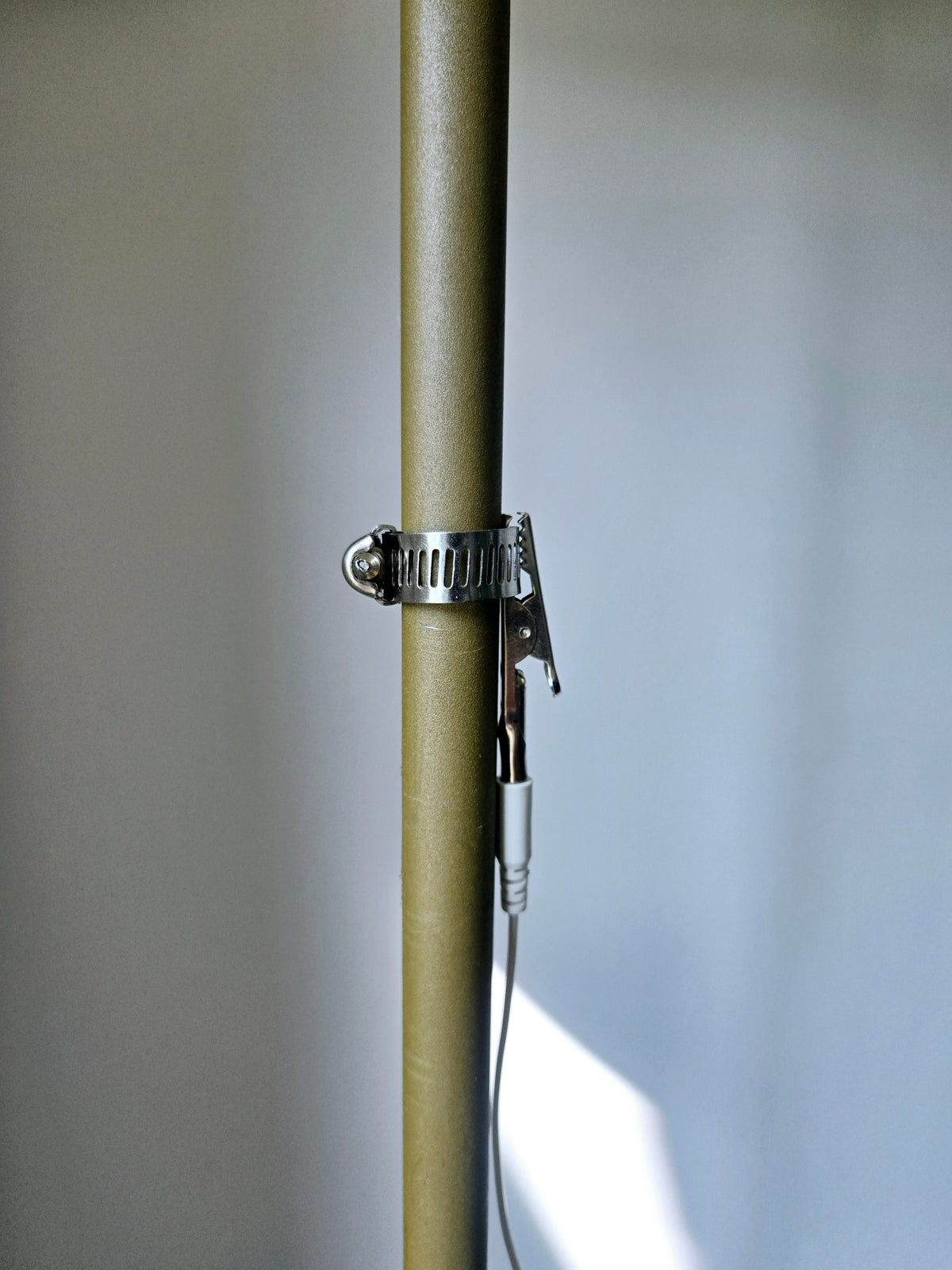 Close-up of the crocodile clip and hose clamp around a heating pipe