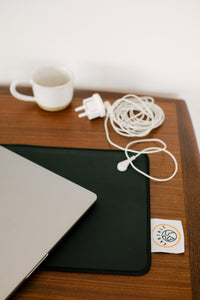 Earthing plug and coiled cable on a desk beside the desk mat and a laptop