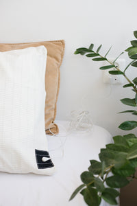 Earthle earthing pillowcase on a pillow on a made bed, with a houseplant beside it