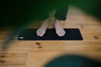 Bare feet on the Earthle earthing mat on the floor, used as a foot mat