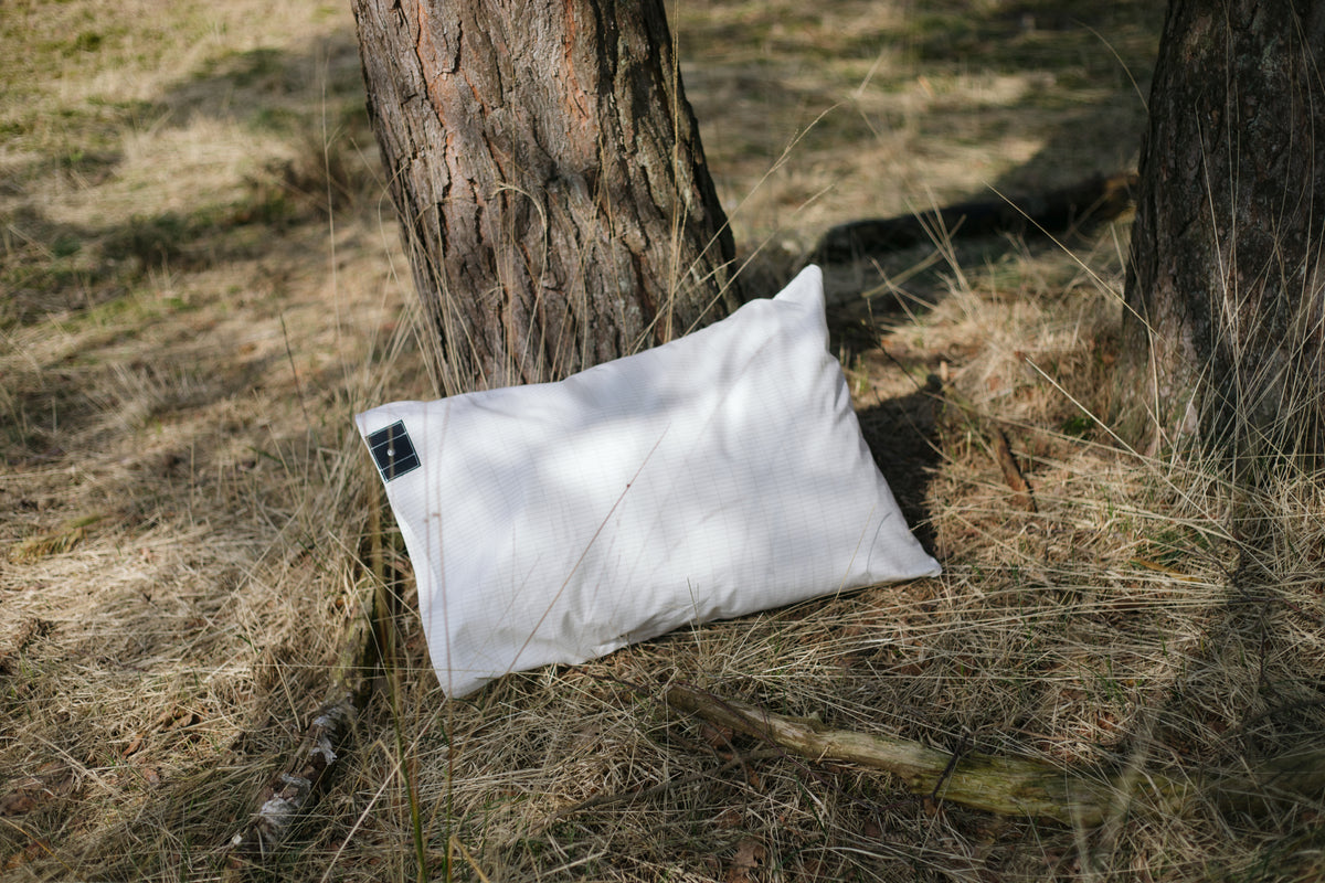 Two Earthle earthing pillowcases in the grass by a pine tree