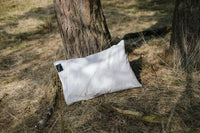 Two Earthle earthing pillowcases in the grass by a pine tree