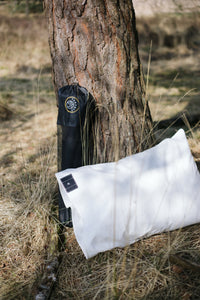 Earthle earthing pillowcase with carry bag against a pine trunk in the woods