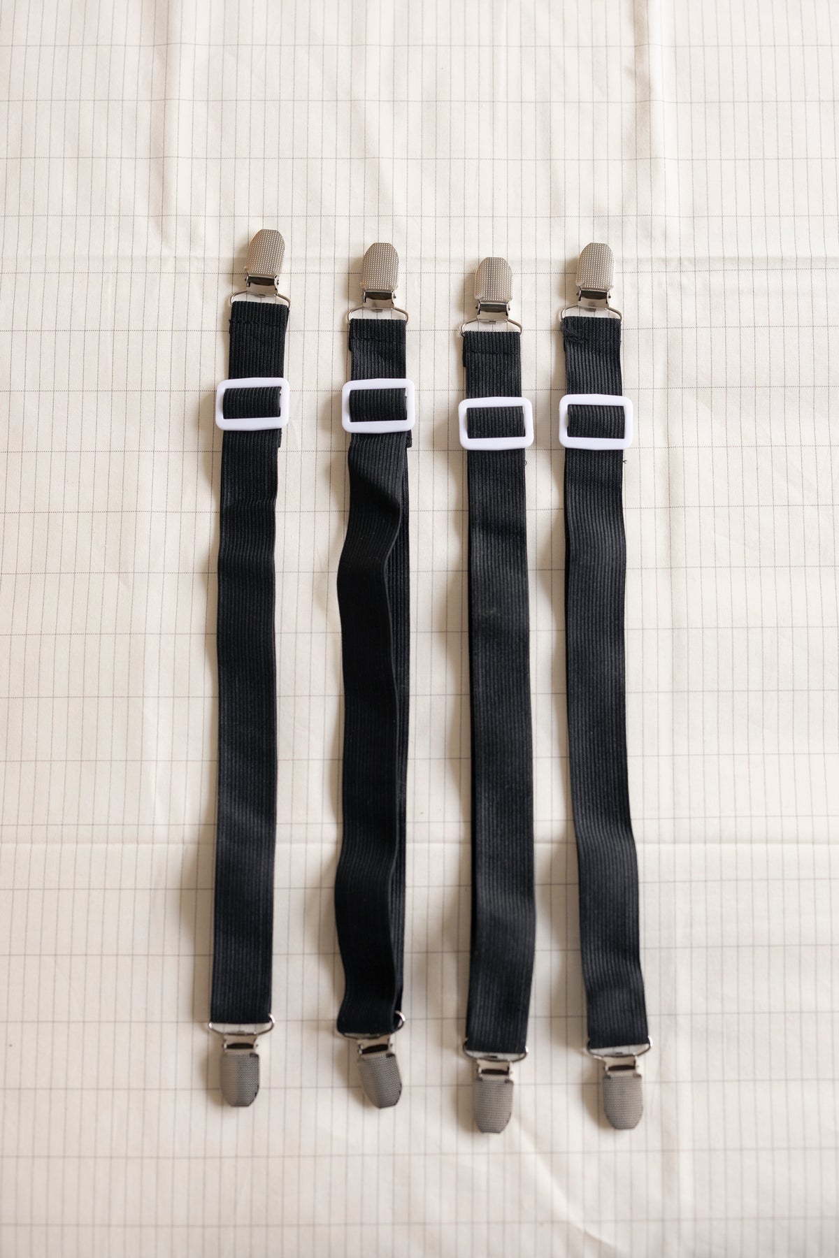 The four Earthle sheet straps side by side, with the clips at both ends