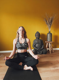 Woman meditating cross-legged on the Earthle earthing yoga mat