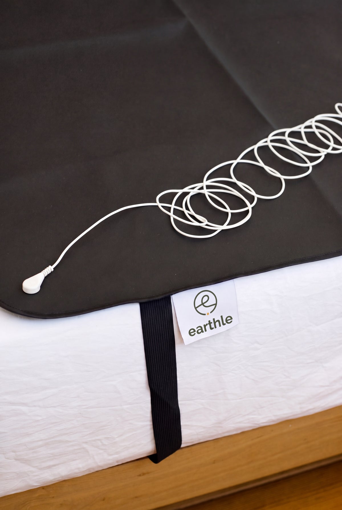 Earthle earthing sleeping mat with the coiled earthing cable on top, 185 x 137 cm
