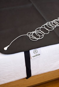 Earthle earthing sleeping mat with the coiled earthing cable on top, 185 x 137 cm
