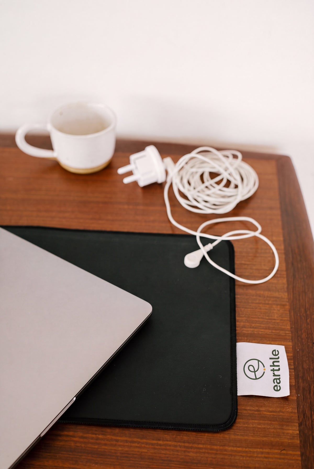 Earthle earthing desk mat on a wooden desk with laptop, coffee cup and the coiled earthing cable