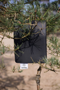 Earthle earthing desk mat hanging on a pine branch in the forest