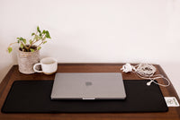 Earthle earthing desk mat on a desk with laptop, plant and mug, cable running to the socket