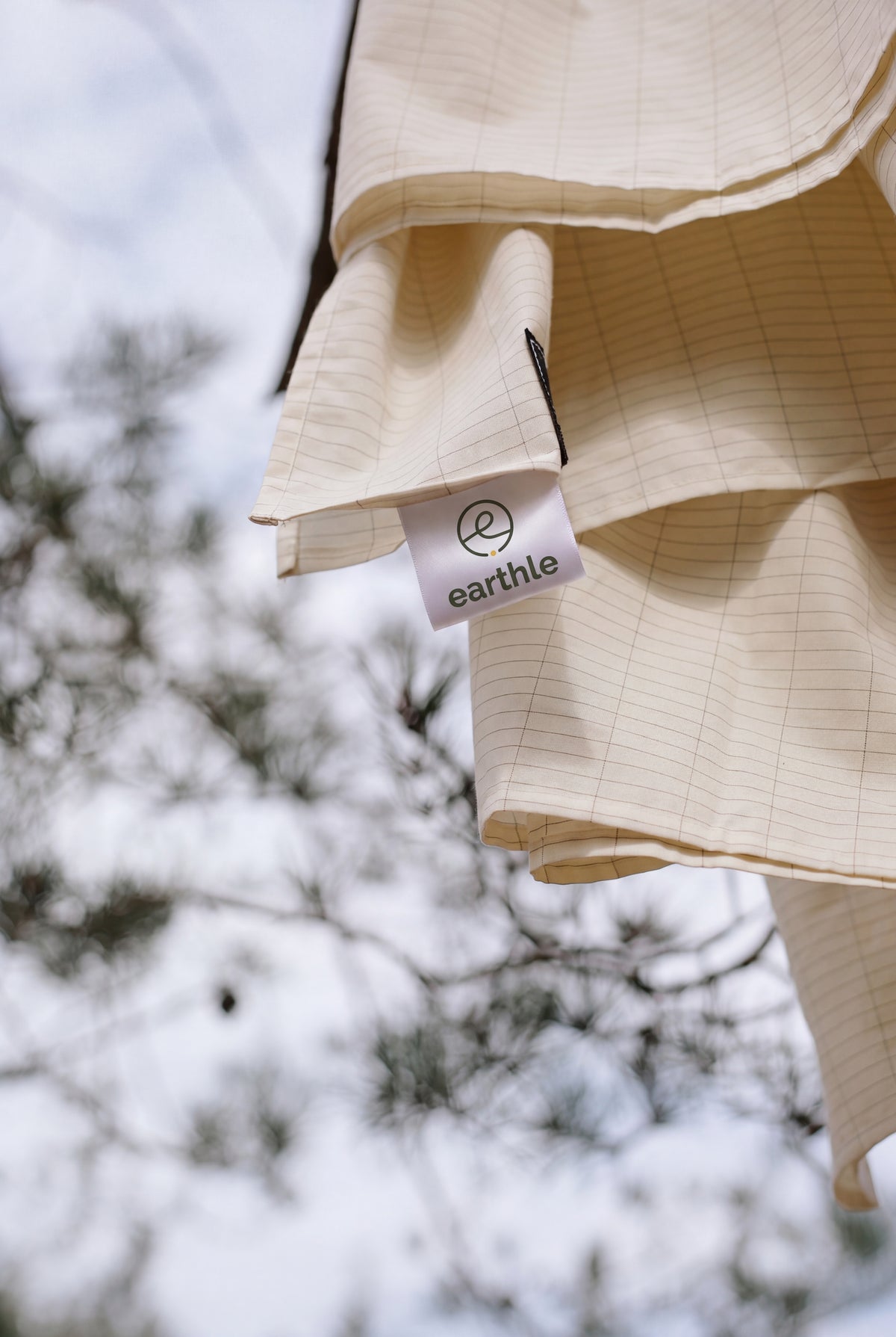 Earthle earthing sheet drying over a pine branch, with the label visible, 203 x 180 cm
