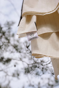 Earthle earthing sheet drying over a pine branch, with the label visible, 203 x 180 cm